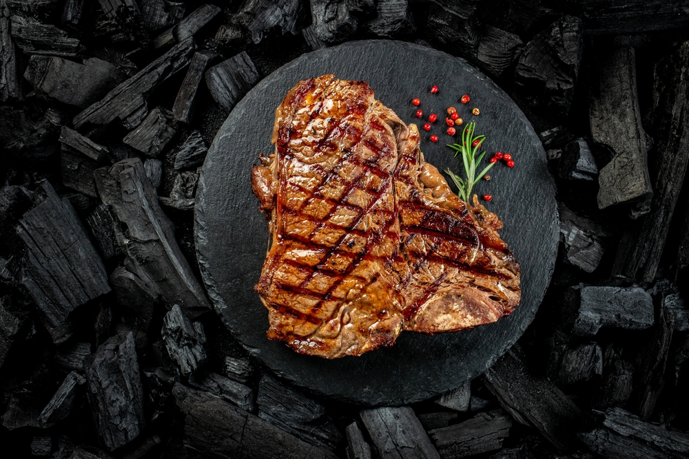 Beef T-bone steaks on BBQ grill coal. porterhouse steak or T Bone Steak. Restaurant menu, cookbook recipe. place for text, top view.