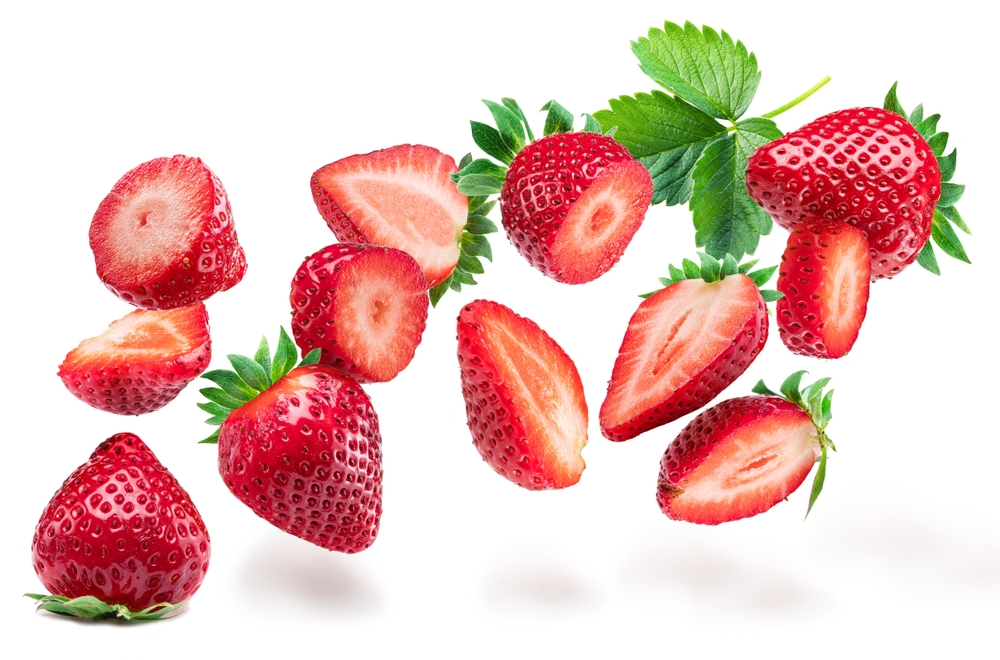 Strawberries and sliced strawberry flying in the air, isolated on white background.