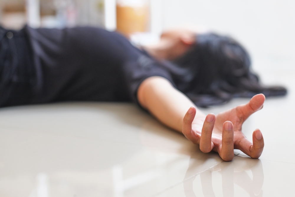 Close-up of hand with epileptic seizures at home against blurred background of fainted woman