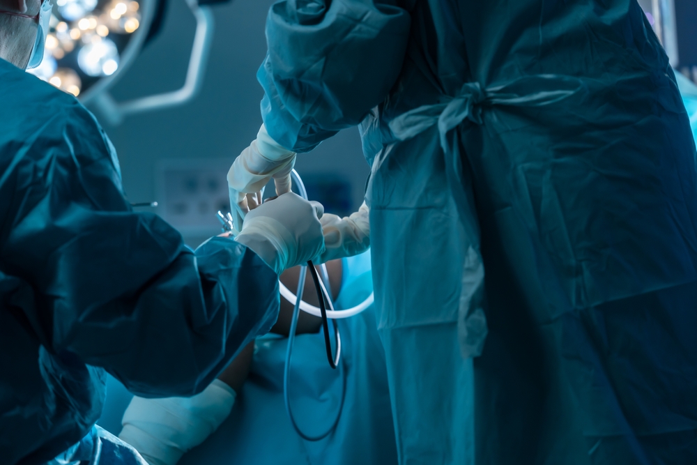 Close-up doctor's hands busy with knee surgery puncture, patient undergoing surgery, doctor's assistant picking up surgical equipment surgeon who is having surgery, for quick timely surgery.