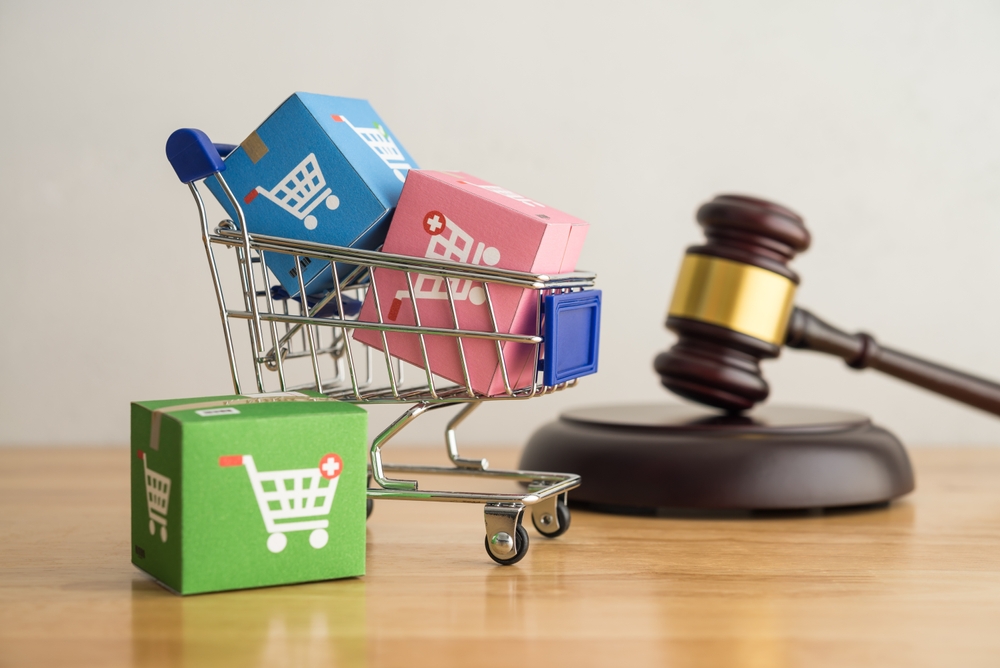Trolley, online shopping boxes and hammer judge gavel on wooden background. Consumer rights and responsibilities to safety, customer protection in online shopping e-commerce, commercial law concept.