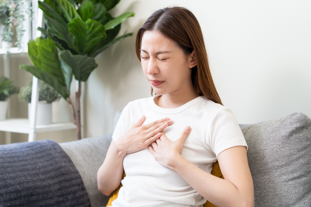 Acid reflux disease, suffer asian young woman have symptom gastroesophageal, esophageal, stomach ache and heartburn pain hand on chest from digestion problem after eat food, Healthcare medical concept