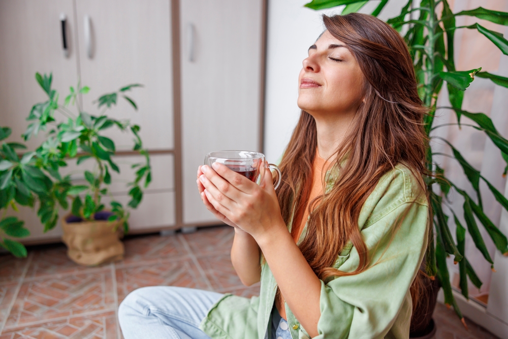 Beautiful young woman relaxing at home sitting at her balcony drinking hot tea