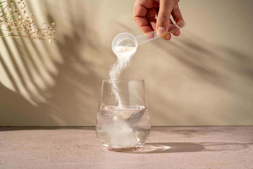 Collagen protein powder scoop and a glass of water. Food beauty and health supplement