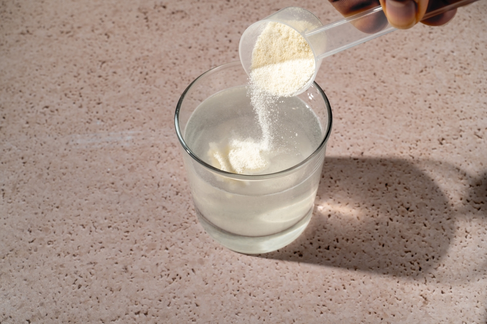 Collagen protein powder scoop and a glass of water. Food beauty and health supplement