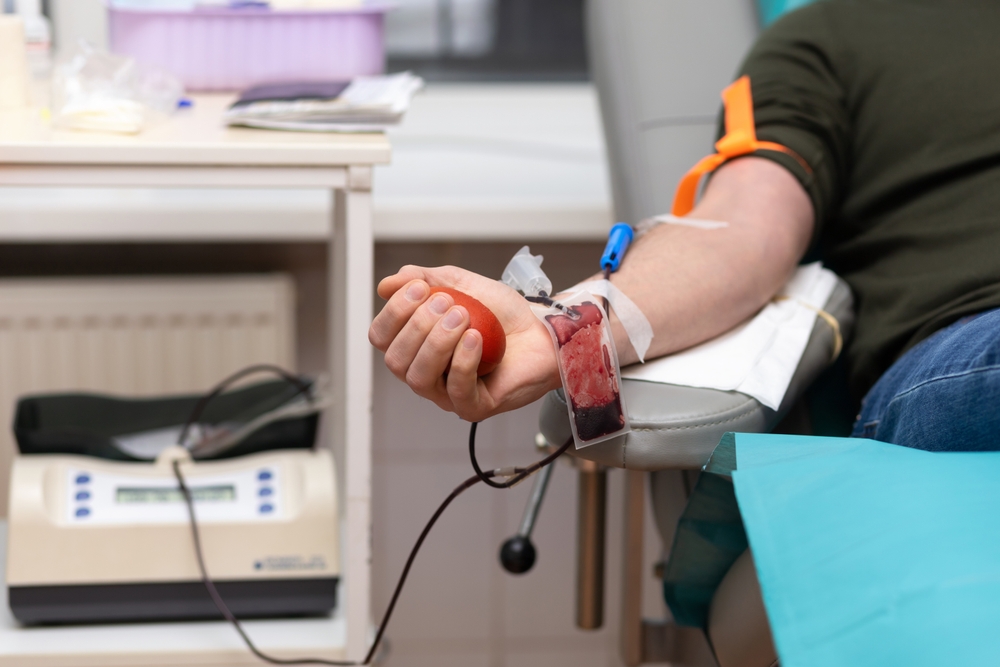 man donor in medical mask for bone marrow donation blood in laboratory. male hand holding red ball, prevention of diseases, illness hemodialysis transfusion in hospital. soft focus