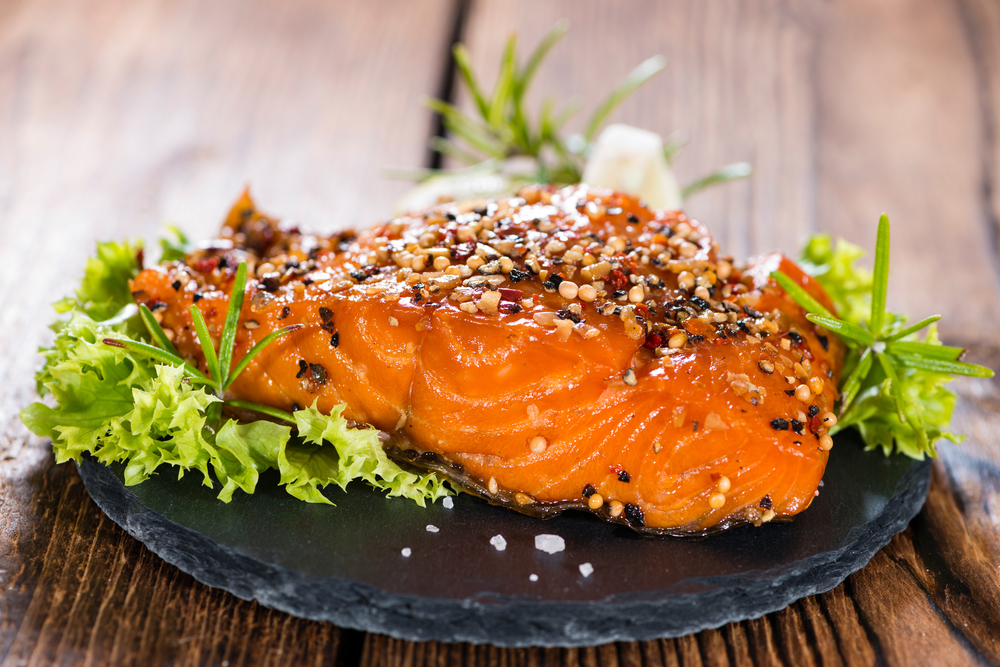 Portion of Smoked Salmon marinated with fresh herbs and spices on wooden background