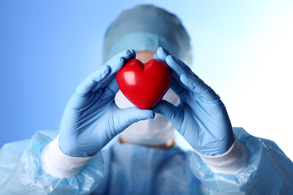Doctor holding decorative heart on blue background
