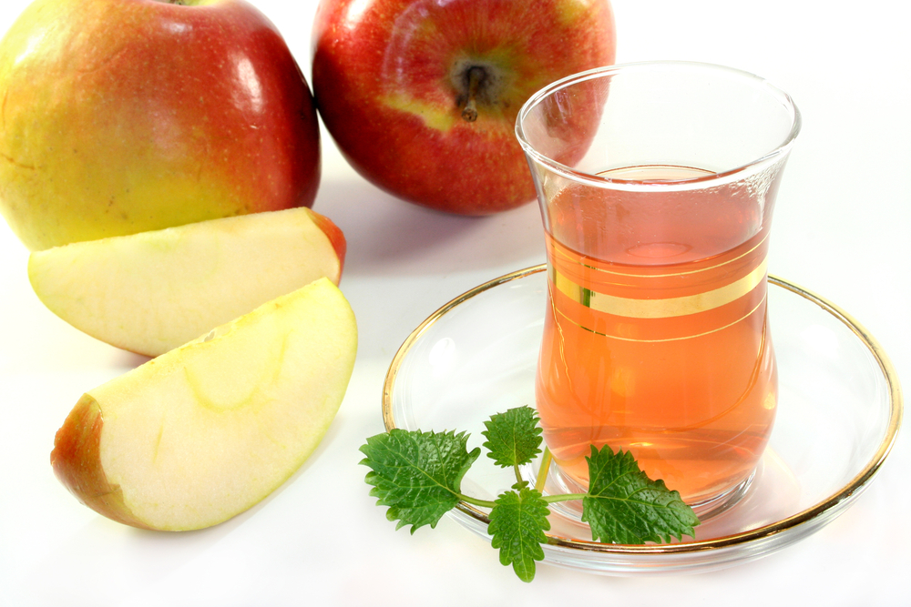 a glass of apple tea with fresh apple and lemon balm