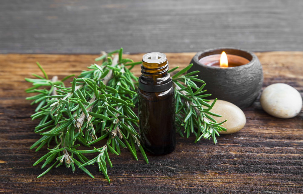 Rosemary aromatherapy oil with rosemary herb on wooden background with candle 