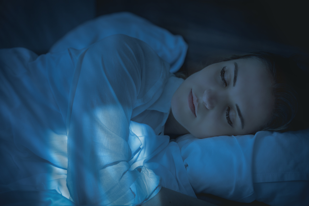 Pretty young woman in bed peacefully sleeping at night