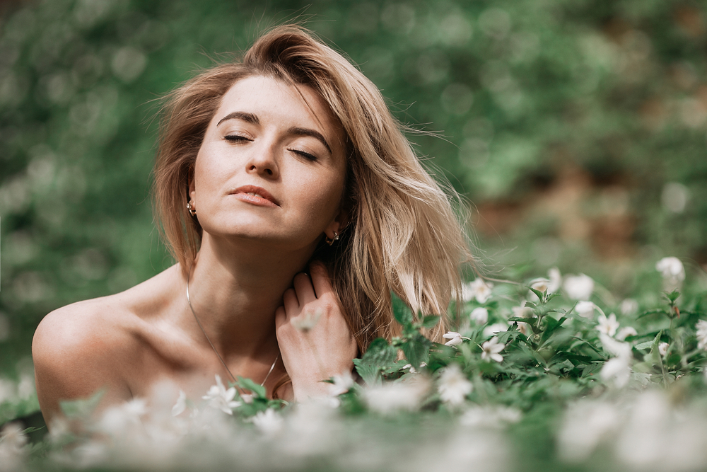 Woman with naked shoulders lies on green grass