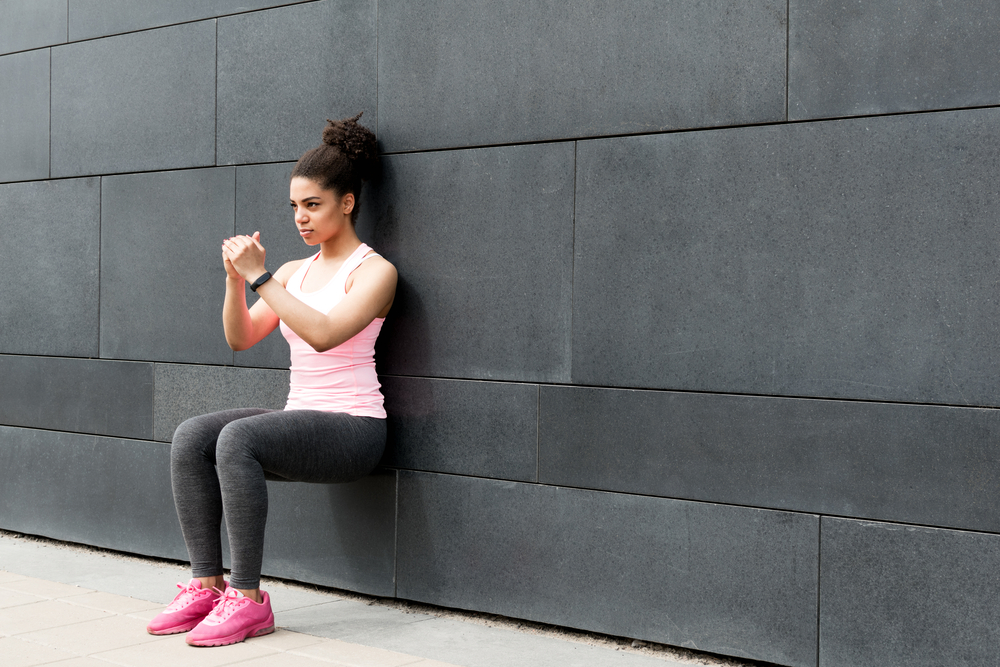 Athlete doing wall squat on city street