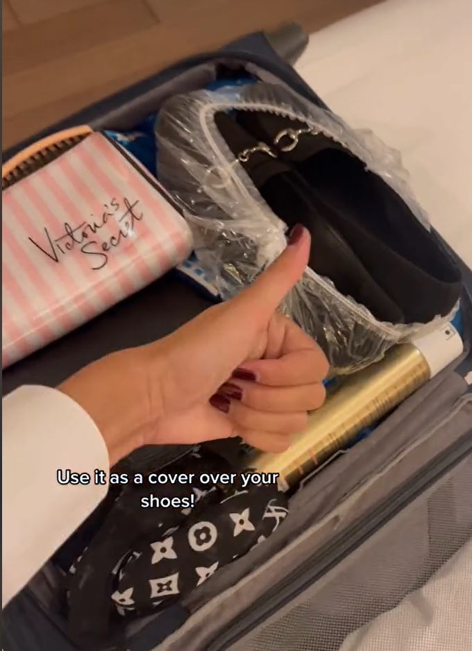 A pair of shoes in a shower curtain packed away in luggage. 