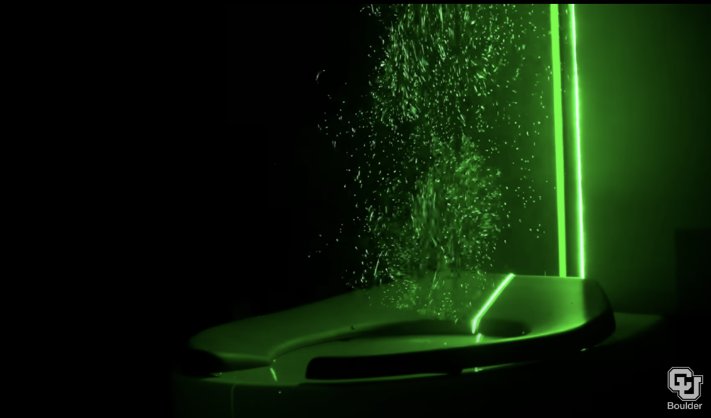 a green laser lights up the particles coming up from the flushing toilet