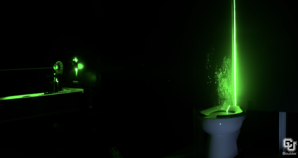 a green laser lights up the particles coming up from the flushing toilet