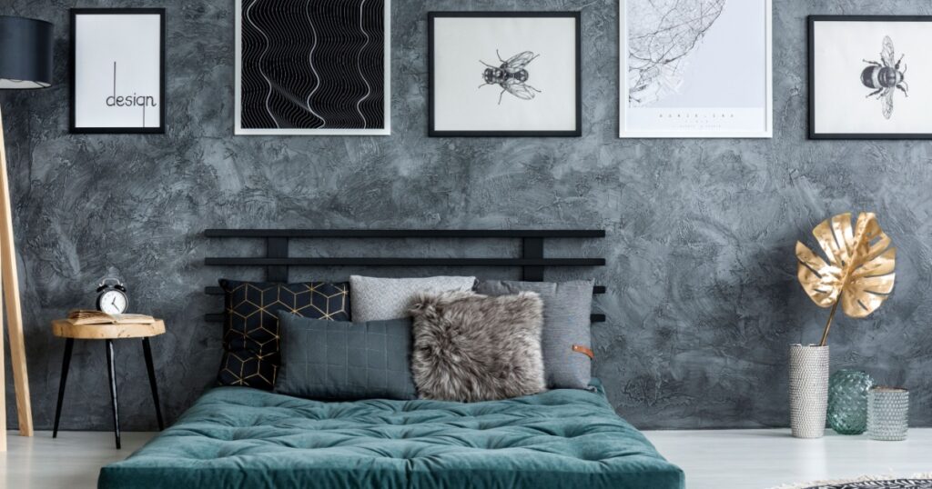Gold leaf near green mattress with pillows in modern bedroom interior with gallery of posters