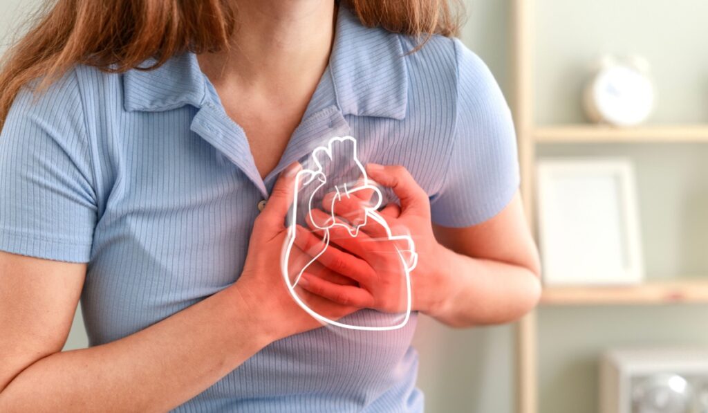 Young woman pressing on chest with painful expression. Severe heartache, having heart attack or painful cramps, heart disease.