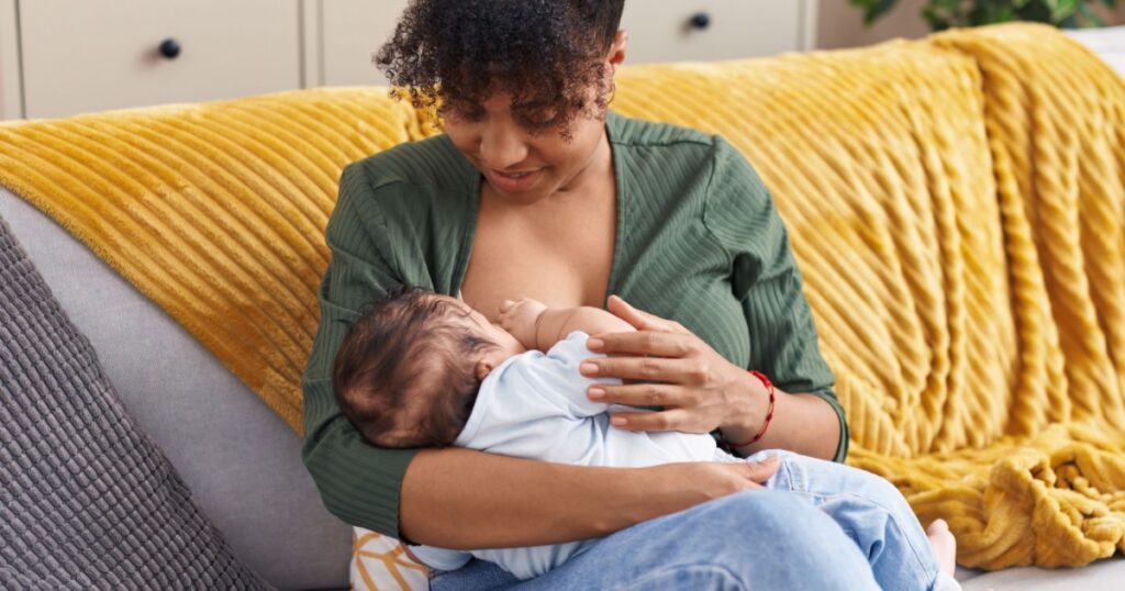 Mother and son sitting on sofa breastfeeding at home 2