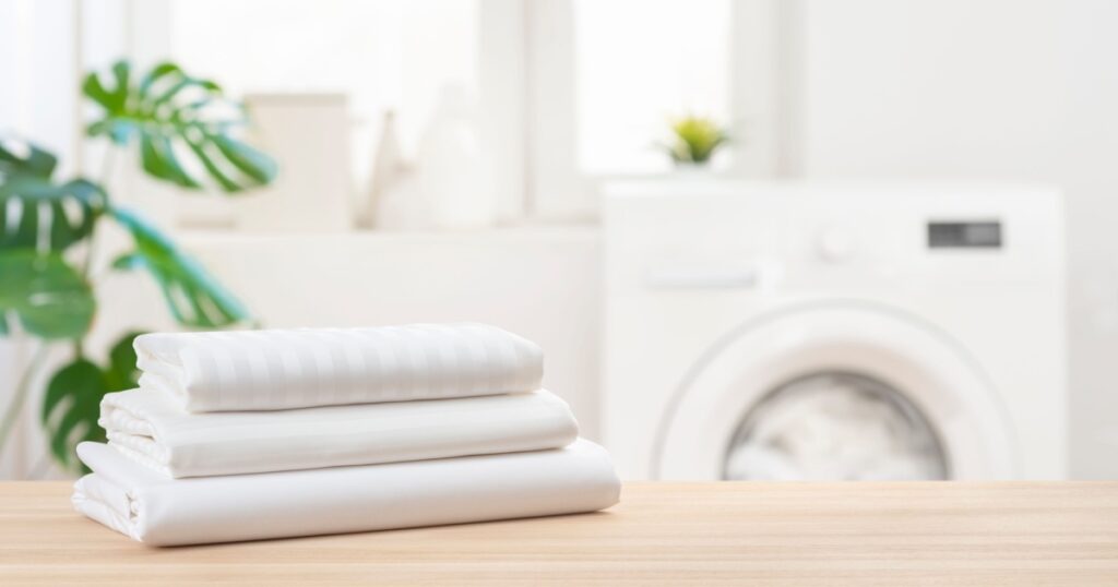 Stack of clean laundry bedding sheets on table in bathroom