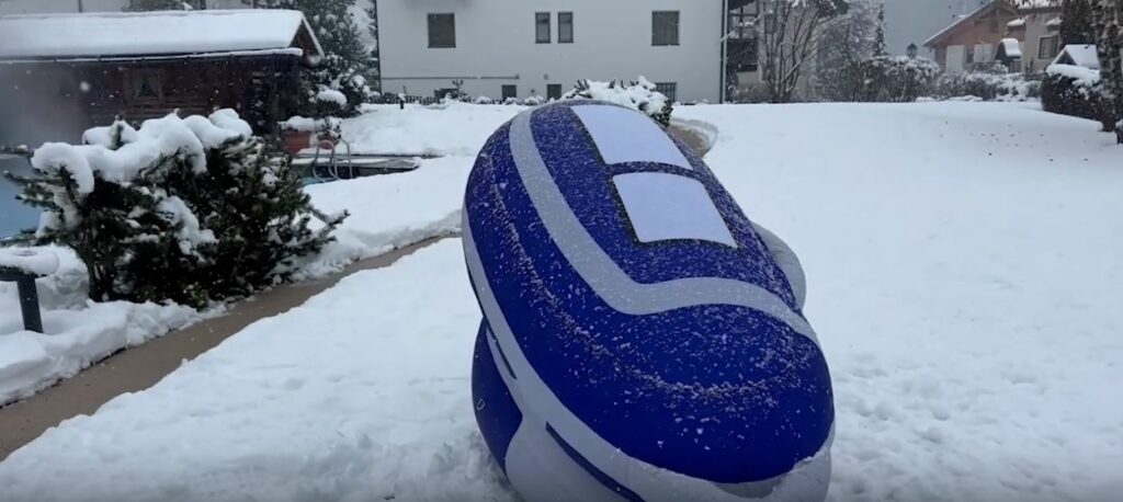 Blue and white suicide pod in the snow. Houses in the background.