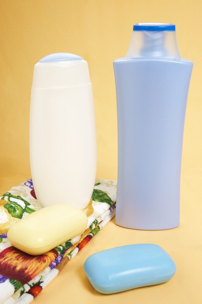 Bars and bottles of soap with a bright towel. Yellow background.