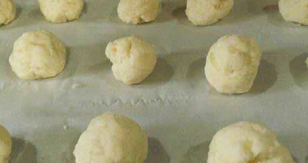 Balls of doughy mixture on parchment paper.