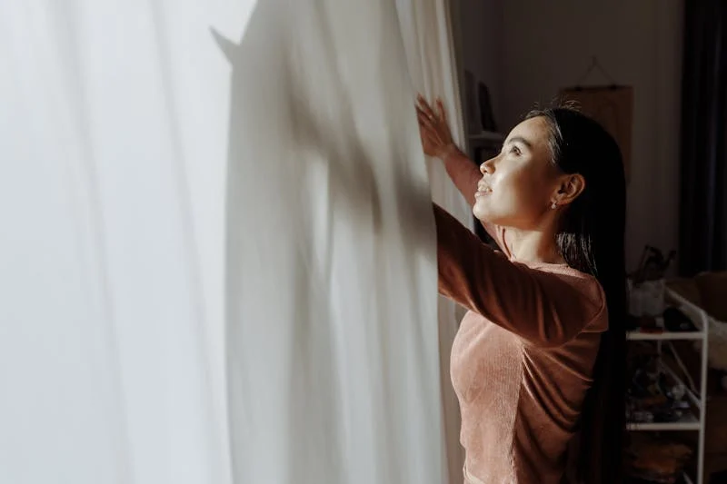 woman opening the curtains