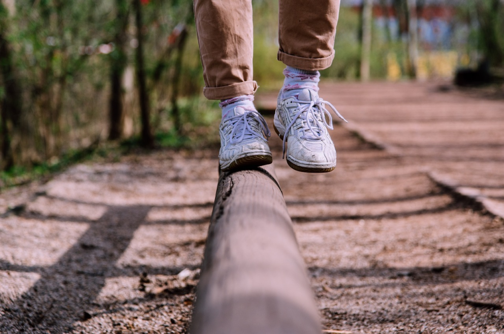 person balancing on a beam of wood