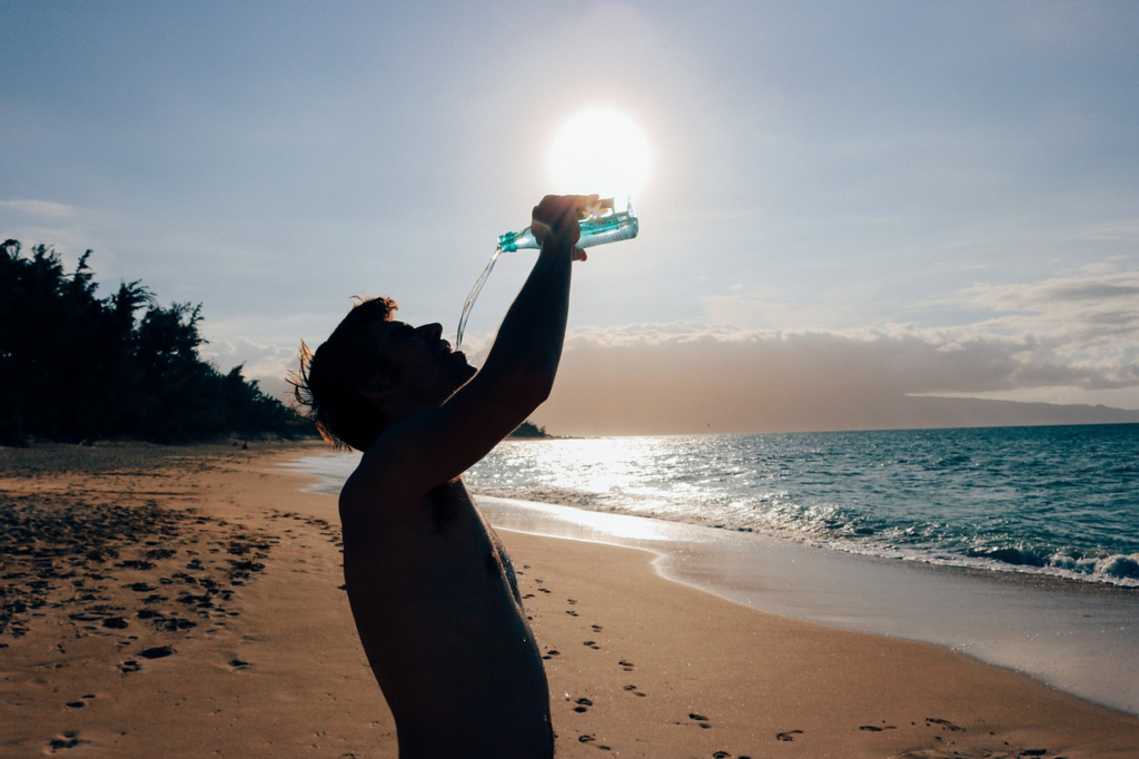 man on the beach drinking water