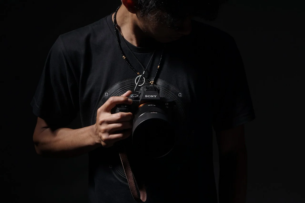 dark-lit picture of man holding a camera