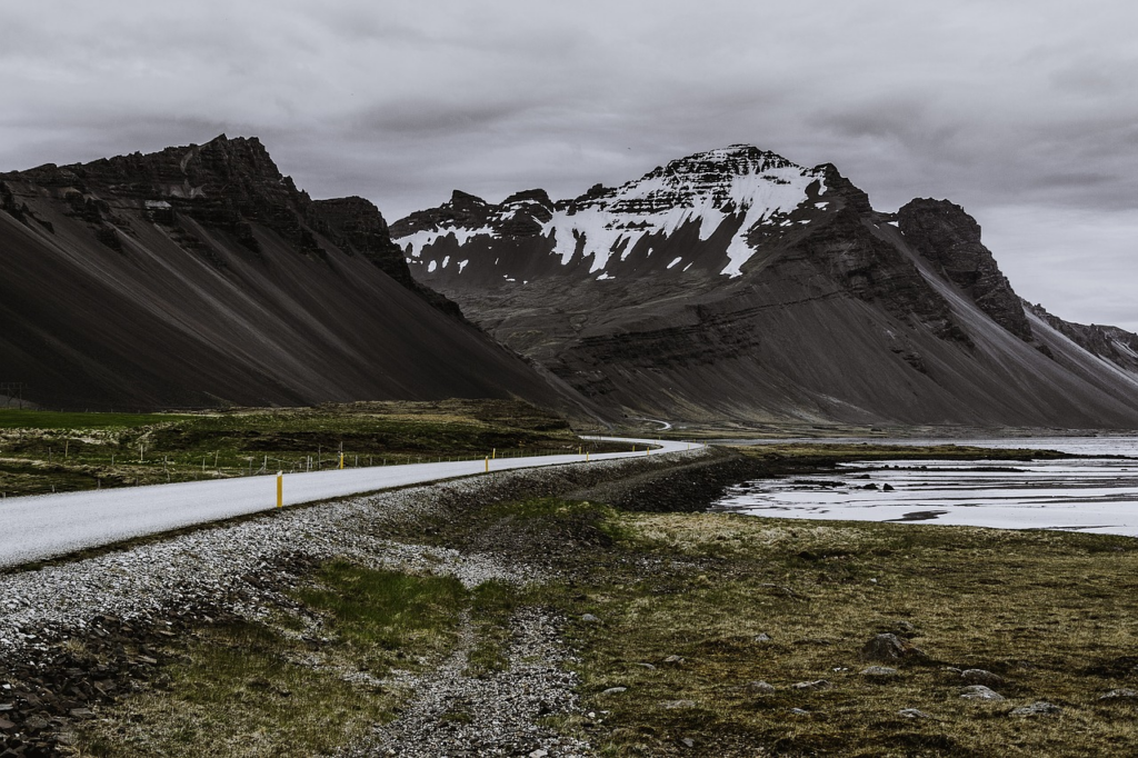 road meandering between shallow water and mountains