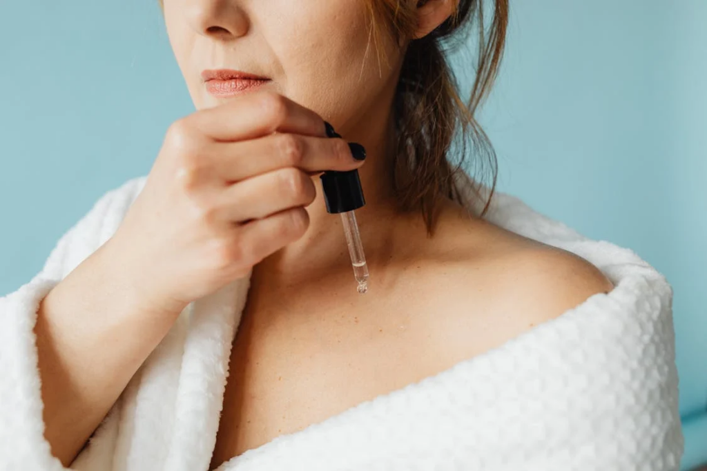 Close-up of Woman Applying a Cosmetic Product with Pipette on Her Collarbones