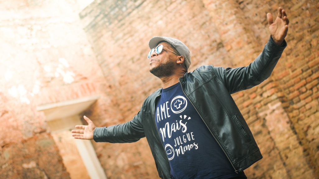 man looking up with arms raised into the light