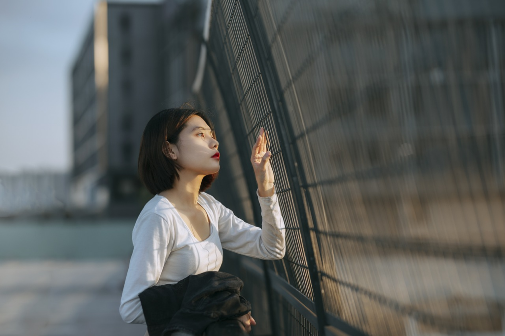 woman looking through a meal fence alone