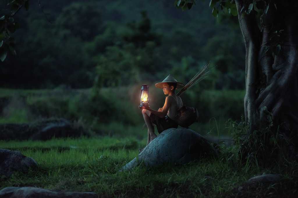 boy sitting by himself with a lantern at night