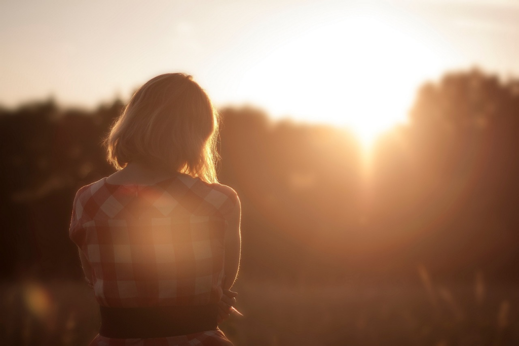 woman with arms crossed looking out towards the sun