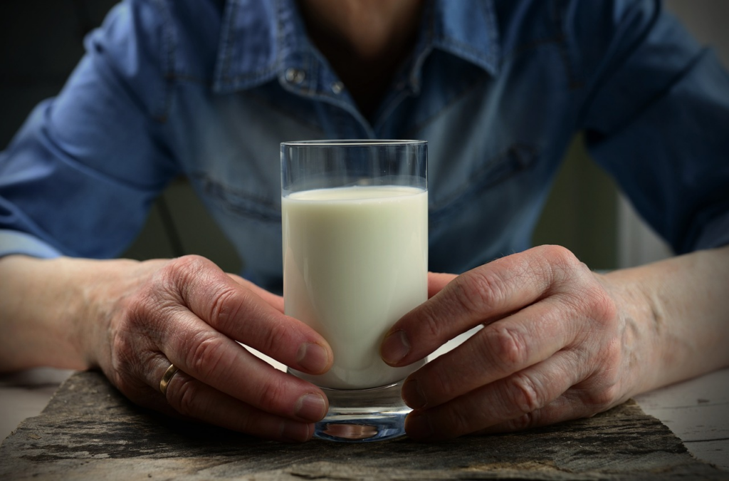 person holding a glass of milk on a table