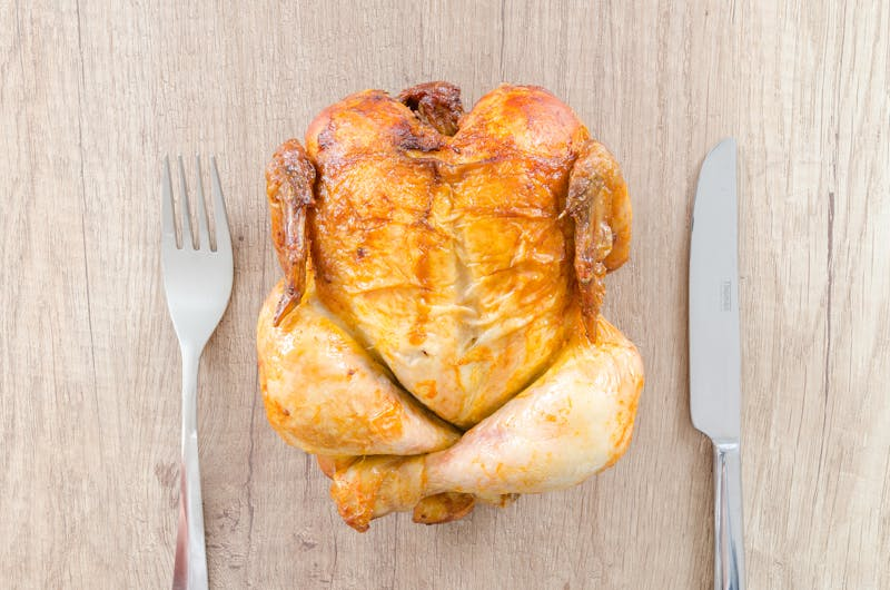 Cooked chicken tied on table between utensils