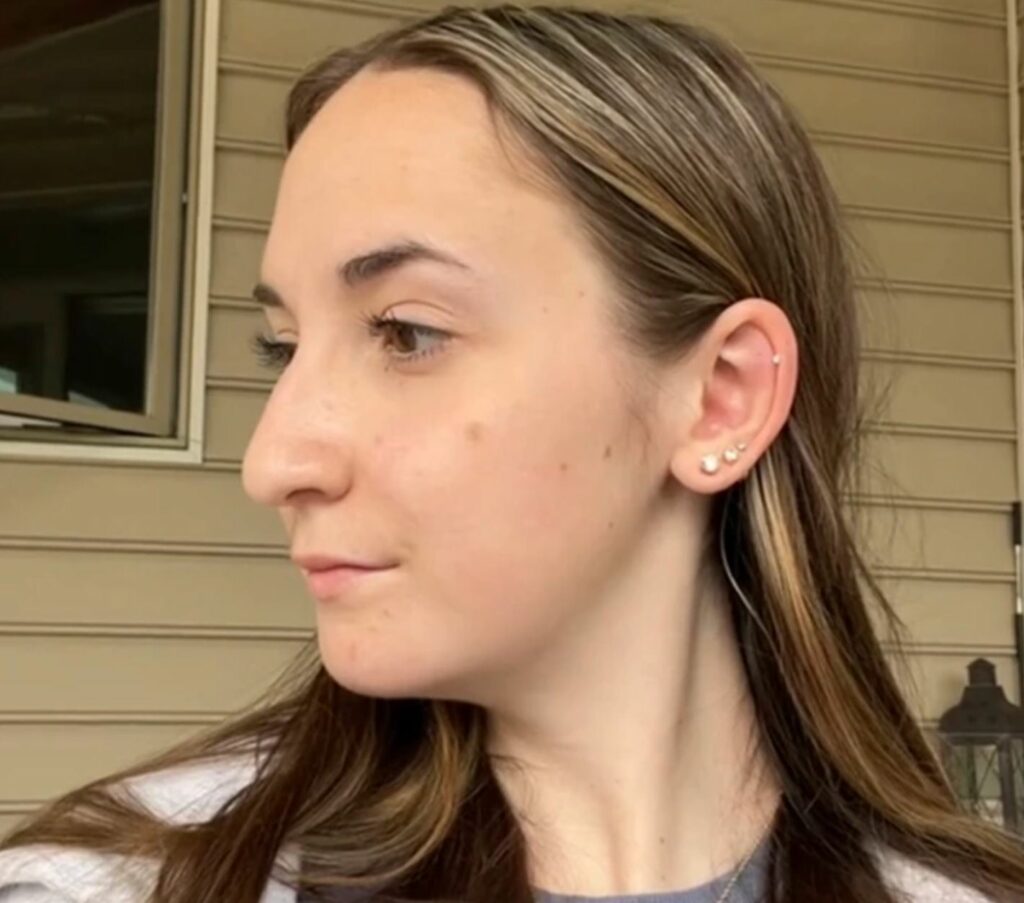 A side view of a young woman. House in the background.
