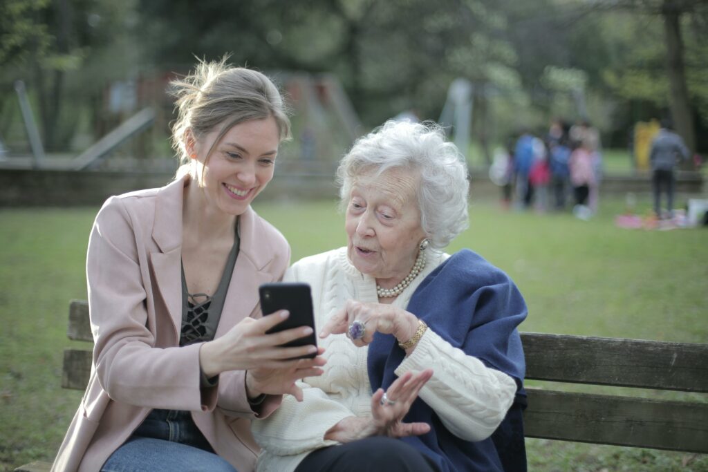 Cheerful senior mother and adult daughter using smartphone