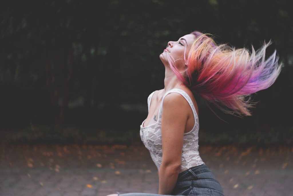 A woman flipping her multi-colored hair. Blurred background.