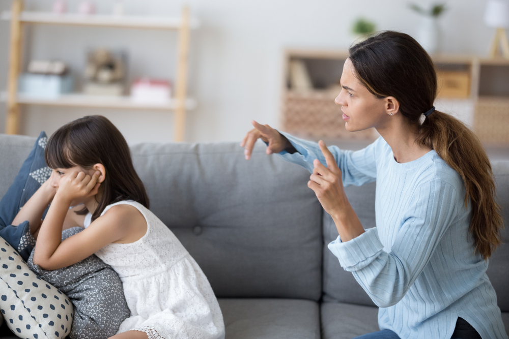 Side view single mother screams shouts at little daughter scolding her. Kid not listen ignoring mom close cover her ears with fingers. Complicated relationships with child and family conflict concept
