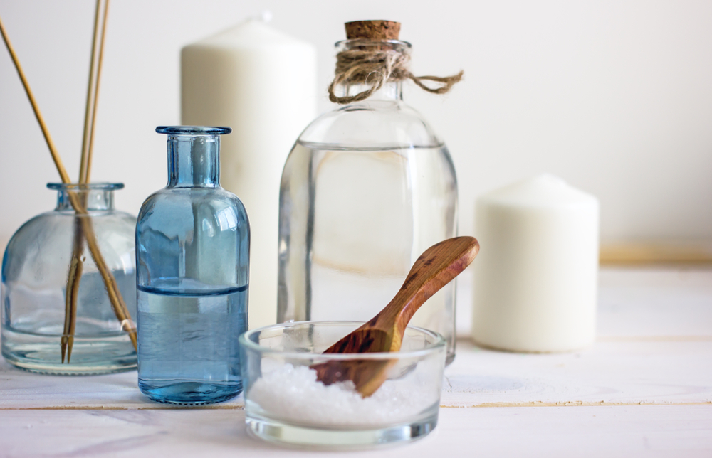 Natural organic cosmetics in glass bottles, near candles, sea salt and incense sticks. Spa skin care, home spa. Bottles with lotion on wooden background.