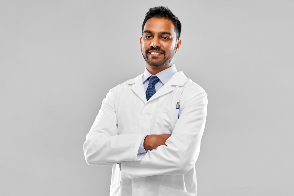 medicine, science and profession concept - smiling indian male doctor or scientist in white coat over grey background