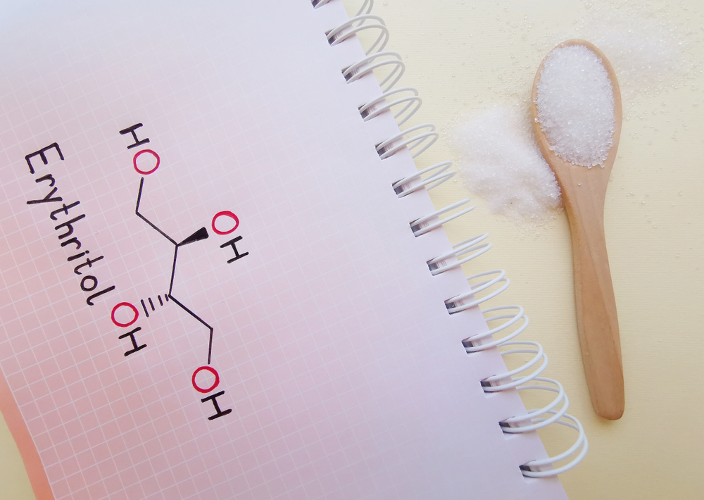Structural chemical formula of erythritol molecule with spoonful of erythritol. It is a sugar alcohol that has been approved for use as a food additive. Noncaloric sweetener, an alternative to sugar.
