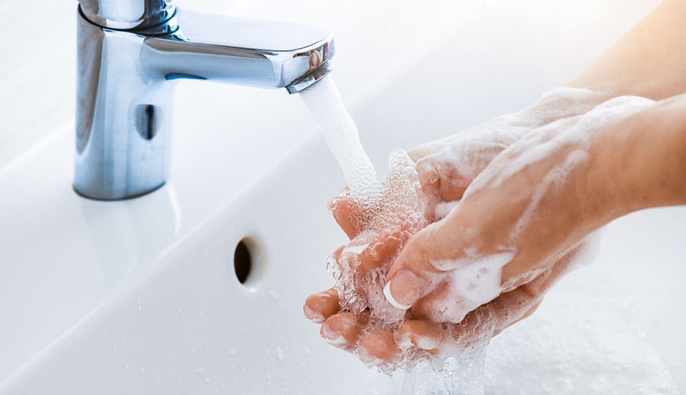 Woman use soap and washing hands under the water tap. Hygiene concept hand detail.
