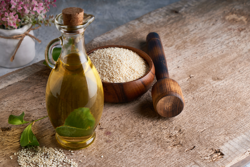 Healthy Sesame oil in glass bottle and sesame seeds on wooden background Copy space Rustic