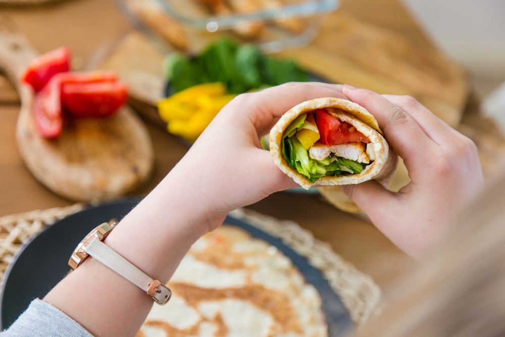 Healthy gluten free, low fat, low carb, paleo tortilla wrap stuffed with vegetables, chicken, peppers tomatoes and green leafy salad