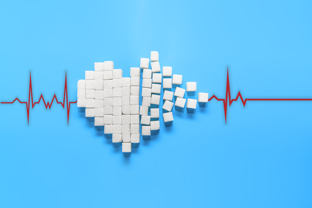 Heartbeat line, cardiogram. Broken heart of pure white sugar cubes on a blue background, the world day of struggle against diabetes